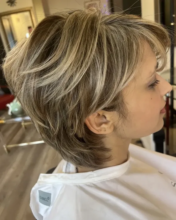 Korte gelaagde pixie met opvallende blonde highlights en een pony opzij