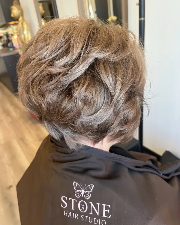 Korte getextureerde laagjescoupe met karamelblonde highlights, afgewerkt bij Stone Hair Studio